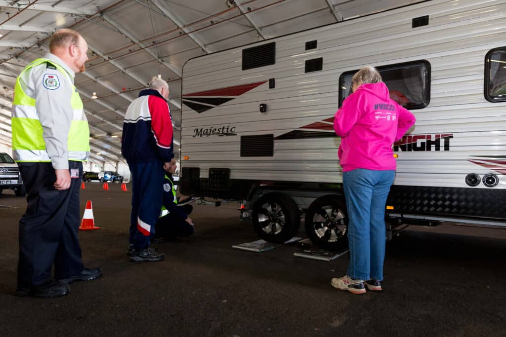 Owners of a caravan looking at the scales that are being used to weigh their caravan